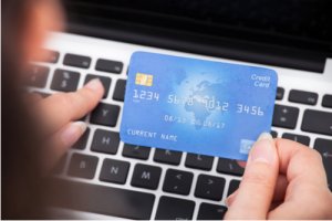 Close-up Of A Person Holding Credit Card Using Laptop